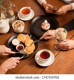 Overhead View Of Roup Of Friends Having Breakfast. Woman Eating Pancakes With Berry Jam, Sweet Dessert And Black Tea Cup On The Background, Close Up. Food And Drink