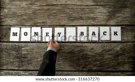 Overhead view of salesman assembling a sign Money back with white cards with letters on them on a textured rustic wooden background. Conceptual of business trade and retail.