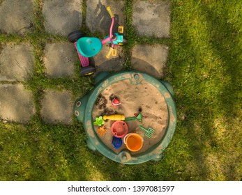 Overhead View Of A Sandbox  With Toys And Bicycle On Lawn