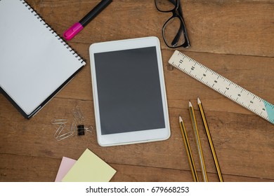 Overhead view of school supplies, digital tablet and spectacles on wooden table - Powered by Shutterstock