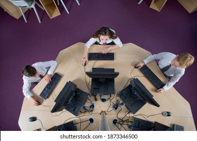 Overhead View Of Schoolboys And Schoolgirl In Private School Uniform Using Computers At The Table In Computer Lab