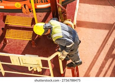 Overhead view of a seafarer performing visual inspection on a ship deck.