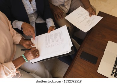 Overhead view of a senior African American woman signing property contract with real estate agent and senior man while sitting on a sofa in living room - Powered by Shutterstock