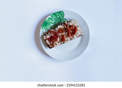 Overhead View Of A Serving Of Tuna And Bell Pepper Tapa On Toasted Whole Wheat Bread On A Plate Decorated With Floral Motifs On A Tray With White Background With Copy Space.