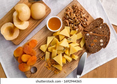 Overhead View Of Set Of Various Appetizers For Wine - Cheese, Walnuts, Dried Apricots, Honey And Canned Pear