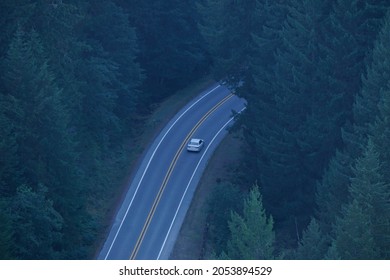 Overhead View Of Silver Car Driving Through Forest On Ribbon Road