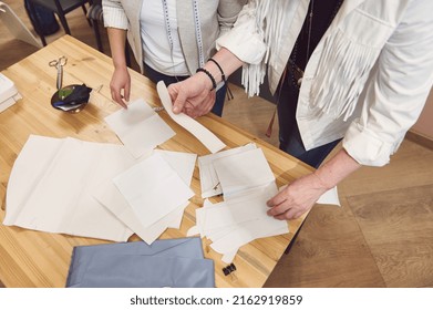 Overhead View Of A Skilled Team Of Fashion Designers Working At A Wooden Table In Clothing Design Studio And Creating Sewing Patterns For New Collection