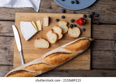 Overhead View Of Sliced Baguette With Blueberries, Strawberry, Cheese And Knife On Serving Board. Unaltered, Healthy Food, French Food, Berry Fruit And Baked Food.