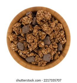 Overhead View Of A Small Wood Bowl Filled With Chocolate Chunk Granola On A White Background.