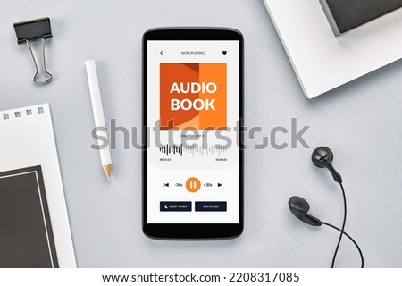 Overhead view of smartphone screen with audio book app open on desk