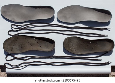 Overhead View Of Some Old Sneaker Insoles And Laces Drying In The Sun On White Plastic On A Tiled Floor Outside.