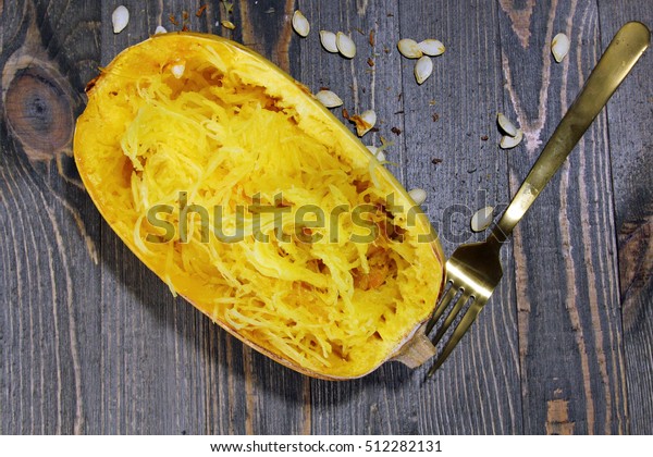 Overhead view of Spaghetti squash on a wooden\
background with squash\
seeds