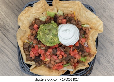 Overhead View Of Steak Taco Salad Served In A Crispy Tostada Bowl, Topped With Sour Cream And Guacomole, Will Fill Your Appetite Perfectly.