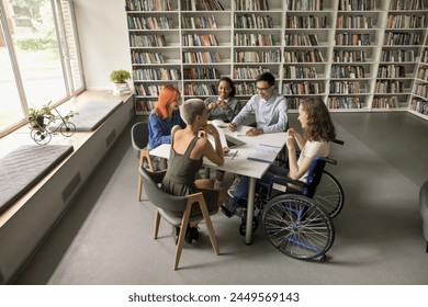 Overhead view students and girl in wheelchair take part in teamwork or educational seminar, literary club participants talking in library. Education, study accessibility for people with disabilities - Powered by Shutterstock