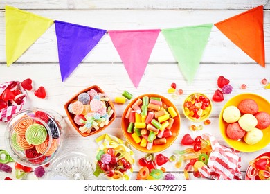 Overhead View Of Table Set With Party Flags In Pink, Green And Yellow Besides Bowls Of Yummy Colorful Confections