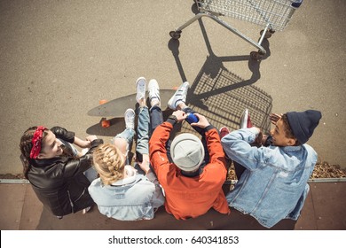 Overhead View Of Teenagers Group Sitting Together And Talking At Skatepark