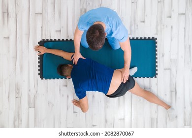 Overhead View Of A Therapist Assisting Male Patient While Stretching His Leg In Hospital. High Quality Photo