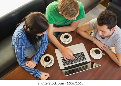 Overhead view of three students using laptop while having coffee at  the coffee shop - Powered by Shutterstock