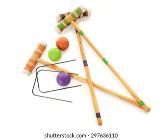 Overhead view of three wooden croquet mallets with matching balls and two black wickets.  On a white background.
