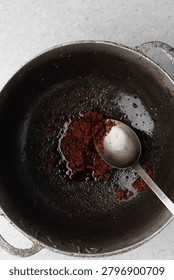Overhead view of tomato paste being fried in a cast aluminum pot, top view of tomato paste being fried to make nigerian jollof rice, process of making jollof rice