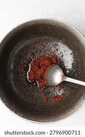 Overhead view of tomato paste being fried in a cast aluminum pot, top view of tomato paste being fried to make nigerian jollof rice, process of making jollof rice
