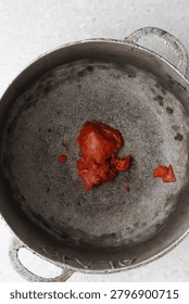 Overhead view of tomato paste being fried in a cast aluminum pot, top view of tomato paste being fried to make nigerian jollof rice, process of making jollof rice