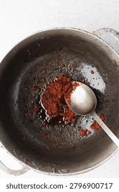 Overhead view of tomato paste being fried in a cast aluminum pot, top view of tomato paste being fried to make nigerian jollof rice, process of making jollof rice