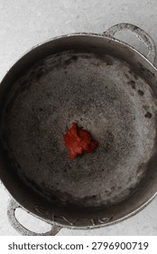 Overhead view of tomato paste being fried in a cast aluminum pot, top view of tomato paste being fried to make nigerian jollof rice, process of making jollof rice