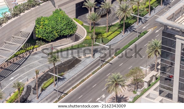Overhead view of transport on a busy road in\
Dubai downtown aerial timelapse. Traffic nearhotel with fountains\
and palms. United Arab\
Emirates