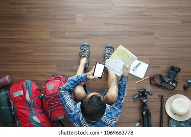 Overhead View Of Traveler Man Plan And Backpack Planning Vacation Travel Idea Concept Trip With Holding Map And Smart Phone. Top View.          