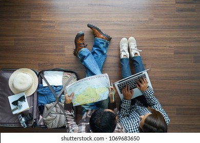 Overhead View Of Traveler's Young Couple Planning Honeymoon Vacation Trip With Working On Laptop Computer And Map. Top View.      