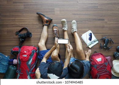 Overhead view of Traveler's Young couple planning honeymoon vacation trip with holding smart phone on wooden floor. Top view travel ideas concept - Powered by Shutterstock