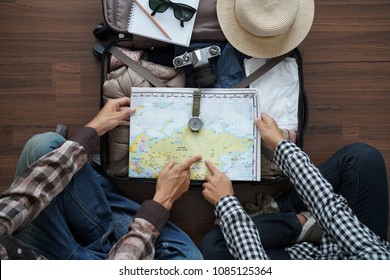 Overhead view of Traveler's Young couple planning honeymoon vacation trip with pointing map. Top view on wooden floor  - Powered by Shutterstock