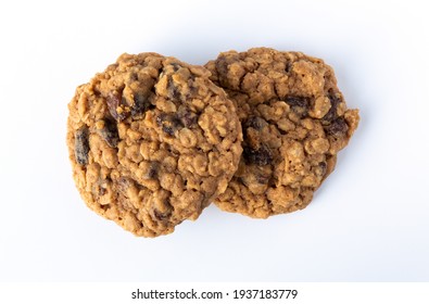 Overhead View Of Two Homemade Oatmeal Raisin Cookies On A White Plate.