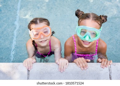 Overhead View Of Two Kids In Swim Masks Looking At Camera In Pool