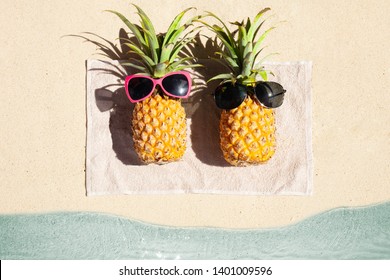 An Overhead View Of Two Pineapple Lying On Towel On The Beach