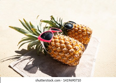 An Overhead View Of Two Pineapple Lying On Towel On The Beach