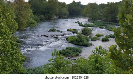 Overhead View Of Water Rushing Over Rocks And Around Small Shrub Covered Islands In Shoal Creek In Joplin Missouri. 