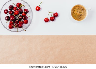 Overhead View White Kitchen Table With Empty Spread Brown Baking Paper, Bowl Of Fresh Ripe Cherries And Cup Of Black Coffee.