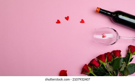 Overhead View Of Wine Bottle And Glass With Red Roses Isolated On Pink Background, Copy Space. Valentine's Day, Flower, Drink And Love Concept.