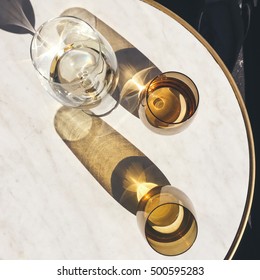 Overhead View Of Wine Glass And Water On A Marble Cafe Table In The Sun