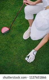 Overhead View Of Woman In Cap And Golf Glove Putting Ball On Green Lawn At Golf Course