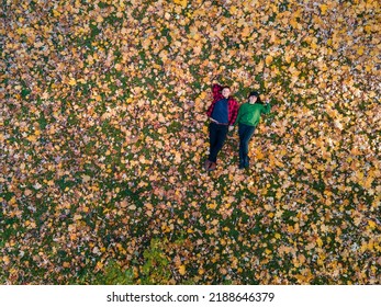 Overhead View Of Woman With Man Laying Down On The Ground Covered With Autumn Leaves Copy Space