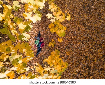 Overhead View Of Woman With Man Laying Down On The Ground Covered With Autumn Leaves Copy Space