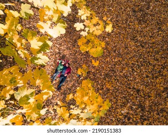 Overhead View Of Woman With Man Laying Down On The Ground Covered With Autumn Leaves Copy Space