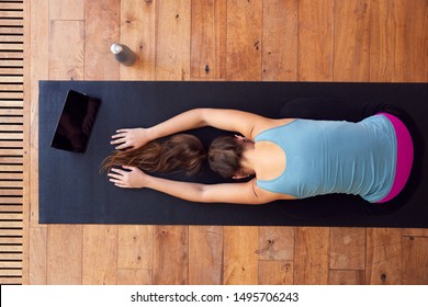 Overhead View Of Woman Stretching On Exercise Mat Using Digital Tablet