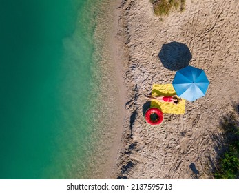 Overhead View Woman Sunbathing At Sandy Beach Blue Lake Water Copy Space