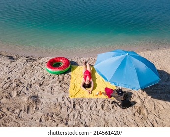 Overhead View Woman Sunbathing At Sandy Beach Blue Lake Water Copy Space