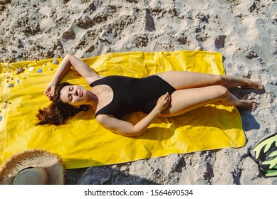 Overhead View Woman Sunbathing At Yellow Blanket At Sand Beach