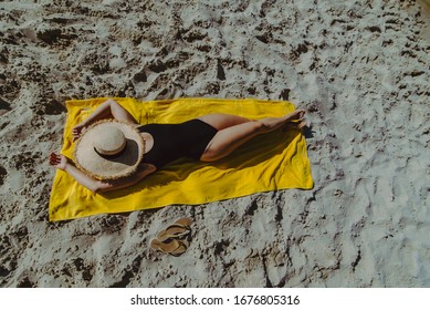 Overhead View Woman Sunbathing At Yellow Blanket At Sand Beach